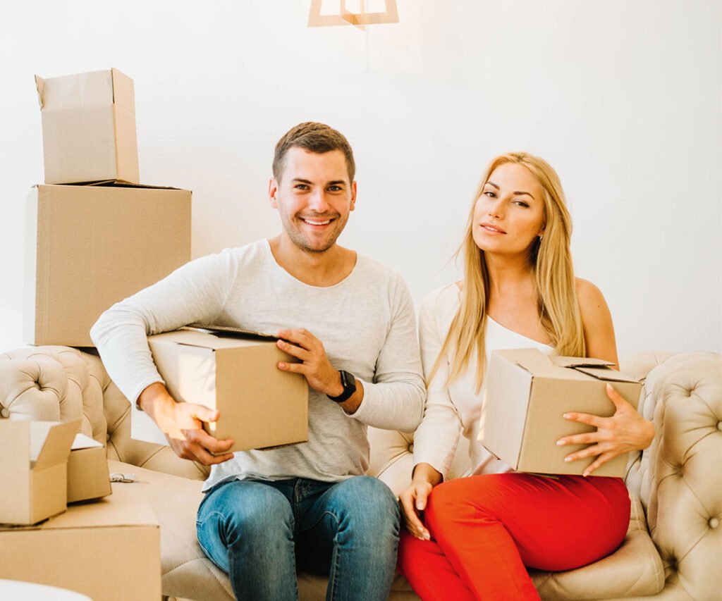 Couple holding moving boxes on a sofa