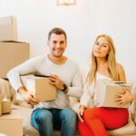 Couple holding moving boxes on a sofa