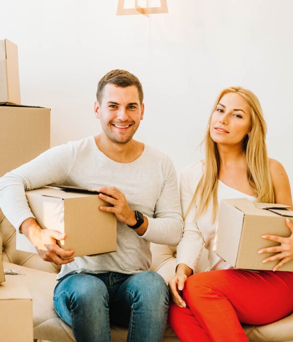 Couple holding moving boxes on a sofa