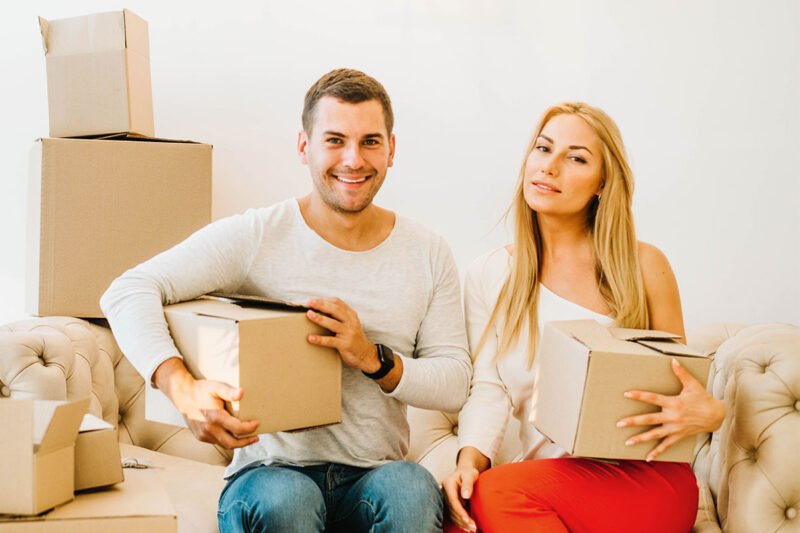Couple holding moving boxes on a sofa