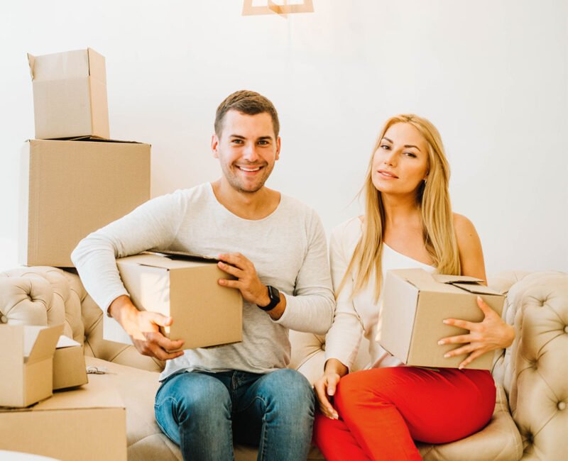 Couple holding moving boxes on a sofa