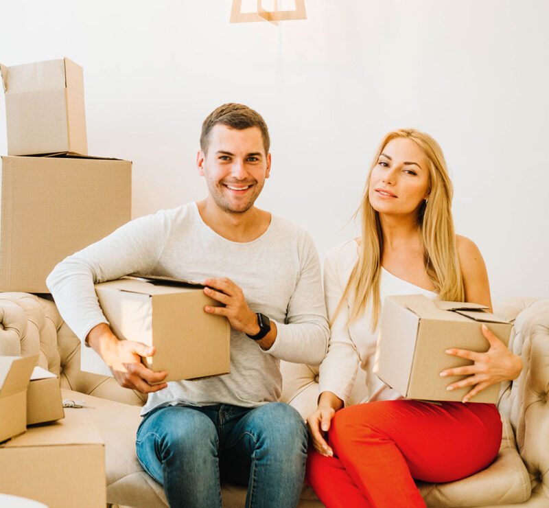 Couple holding moving boxes on a sofa